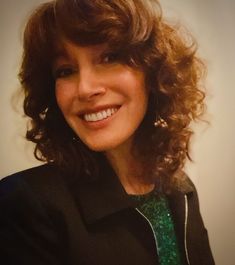 a woman with curly hair smiling for the camera