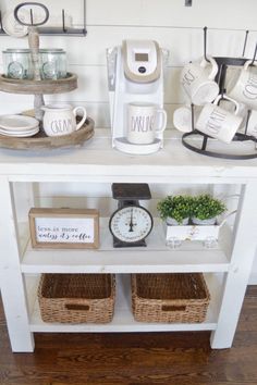 a white table topped with lots of cups and saucers next to a clock on top of a shelf