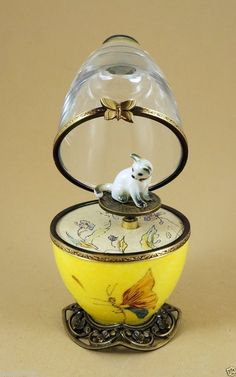 a yellow vase with a small white dog in it's glass dome on top