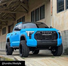 a blue toyota truck parked in front of a building with the words toyota written on it