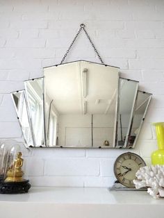 a mirror hanging on the side of a white brick wall next to a yellow vase