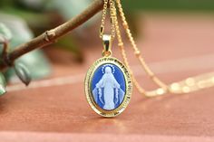 "Miraculous Medal cameo pendant, 18 k gold plating over sterling silver, Our Lady of grace necklace pendant, blue agate Virgin Mar pendant  This miraculous medal cameo pendant is made with 18 k gold platted sterling silver 925  and blue Agate paste combined with resin glue. Medal is made with two parts : - Sterling silver frame with gold plating  - Blue agate Our Lady of Grace centrepiece  On sterling silver frame in front is written in French language: \" O Marie concue sans peche priez pour no Elegant Sterling Silver Necklace With Miraculous Medal, Elegant Commemoration Jewelry With Charms, Elegant Miraculous Medal Jewelry, Elegant Round Miraculous Medal Jewelry, Elegant Miraculous Medal Jewelry Gift, Elegant Miraculous Medal Jewelry For Gift, Elegant Oval Necklace With Miraculous Medal, Blue Hallmarked Medallion Jewelry, Miraculous Medal Pendant For Memorial