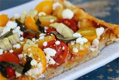 a slice of pizza with tomatoes, cheese and other toppings sitting on a white plate