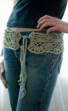 a woman is holding her jeans with crochet on it and the bottom part of her pants has an attached belt