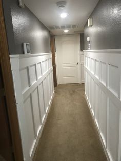 an empty hallway with white paneling on the walls and carpet in front of it