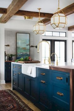 a kitchen with blue cabinets and brass fixtures, an area rug and chandelier