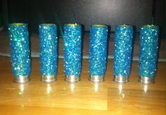 five blue vases are lined up on a wooden table with glitter in them and one is empty