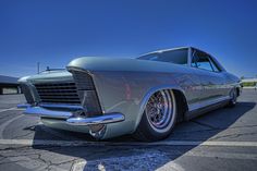 an old car parked in a parking lot with the sun shining on it's side