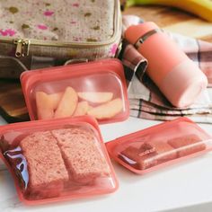 three plastic containers filled with food sitting on top of a table next to a purse