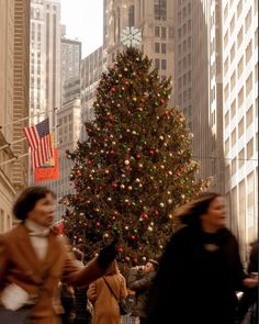 people walking in front of a large christmas tree