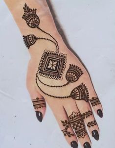 a hand with henna tattoos on it and some beads hanging from the middle of it