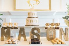 a table topped with cakes and cupcakes next to a sign that says mason