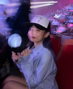 a woman in a baseball cap is holding a light up ball and looking at the camera