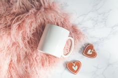 two heart shaped cookies next to a coffee mug on a fluffy pink blanket with the words mug mockup