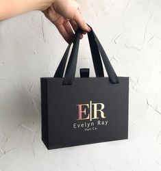 a person holding a black shopping bag with the eir logo on it, in front of a white wall