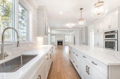 a large kitchen with white cabinets and wood floors