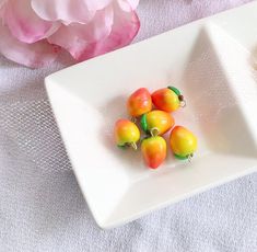 there is a white plate with small fruit on it and pink flowers in the background