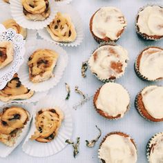 several cupcakes with white frosting on paper plates next to other pastries