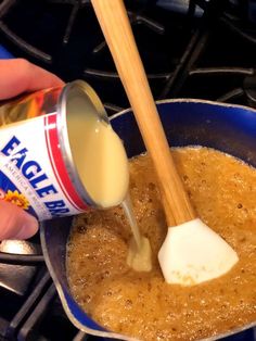 a person pouring sauce into a pan on top of a stove with a wooden spoon