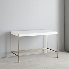 a white table with gold legs against a gray wall