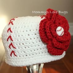 a crocheted baseball hat with a flower on it sitting on top of a wooden table