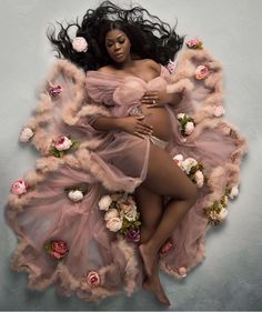 a pregnant woman laying on top of flowers