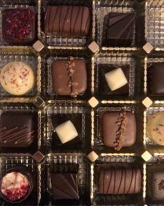 many different types of chocolates are on display in trays with white and brown icing