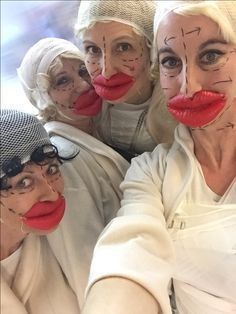 four women with painted faces pose for a photo in front of the camera, wearing white clothing and red lipstick