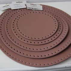 four brown plates with holes on them sitting on a shelf next to a white wall