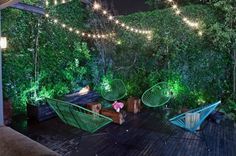 an outdoor deck with hammock chairs and string lights strung across the top area