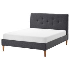 a bed with a gray headboard and white sheets on it's bottom half