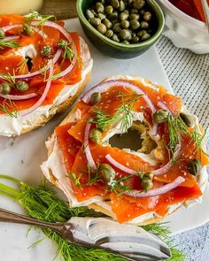 two bagel sandwiches topped with fresh vegetables and capers