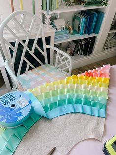 there are many different colored ribbons on the table and in front of it is a bookcase