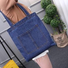 a woman is holding a large blue jean bag