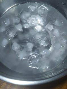 an ice bucket filled with water and ice cubes on top of a wooden table