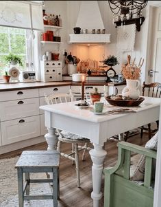 a white table and chairs in a room with wooden floors, cabinets and drawers on the wall