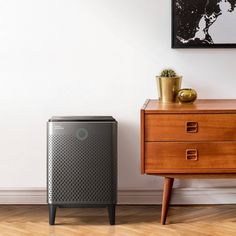 an air purifier sitting on top of a wooden dresser next to a plant