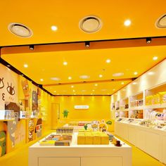 the interior of a store with yellow walls and ceiling lights on either side of the counter