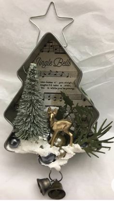 a small christmas tree with bells and evergreens on it's sides, surrounded by sheet music