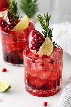 two pomegranate cocktails with lime and rosemary garnish