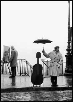 a man holding an umbrella standing next to a musical instrument