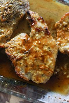 three pieces of meat sitting on top of a pan covered in gravy and sauce