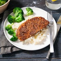 a white plate topped with meat and broccoli on top of a wooden table