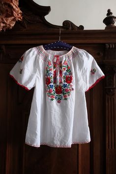 Amazing Hungarian folk blouse from the 1980s. Comfortable white flowy fabric with vibrant flowers and vines embroidered on the front and on the sleeves. Split neckline with tie band. Borders with folklore elements on the front. Multi-tonal stitching around the neckline. Short wide sleeves with crochet piping on the sleeve ends.  Looks great with a pair of highwaist flare jeans and combined with a pair of clogs!  ERA: 1980s BRAND: No brand label anymore COLOR: White, red, green, pink, lilac, blue Summer Folk Peasant Top With Embroidered Sleeves, Spring Folk Embroidered Peasant Top, White Folk Peasant Top For Festival, Spring Multicolor Embroidered Peasant Top, Folk Style Peasant Top With Embroidered Sleeves For Festival, Folk Style Floral Embroidered Peasant Top For Spring, Folk Style Peasant Top With Floral Embroidery For Spring, Multicolor Embroidered Peasant Top For Spring, Bohemian White Peasant Top With Embroidered Sleeves