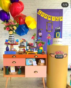 an assortment of colorful balloons and decorations in front of a purple door with a yellow refrigerator