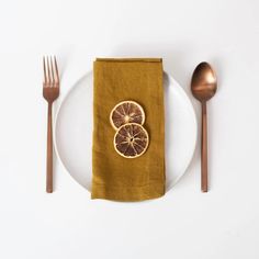 a white plate topped with two orange slices next to a fork and knife on top of a table