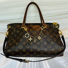 Authentic Louis Vuitton Monogram Pallas Noir Leather Handbag W/Louis Vuitton Authentic Charm Comes With: Monogram Shoulder Strap (Removable) Louis Vuitton Dust Bag Louis Vuitton Bag Charm/Key Ring Fleur De Monogram M6511 Fabric/Material: Monogram Canvas Leather (Black Outer Inserts; Brown Handles) Interior: Black Microfabric (With Patch Pockets) Hardware Color: Gold Original Owner: Used Wear Shown On Metal (Pics): 1- Metal At Bottom Of Handbag 2- Where Charm Attaches At Handles 3- Very Small Scr Louis Vuitton Dust Bag, Bag Louis Vuitton, Monogram Bag, Vuitton Bag, Canvas Leather, Louis Vuitton Handbags, Leather Handbag, Monogram Canvas, Authentic Louis Vuitton