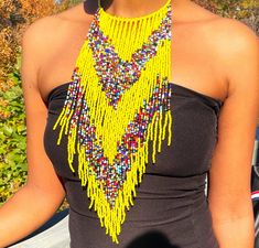 Eye-catching design: Exaggerated tassel bib necklace with African beaded detail Versatile accessory: Perfect for adding a pop of color and texture to any outfit High-quality material: Made with durable acrylic beads and braided cord for long-lasting wear Statement piece: Makes a bold statement and adds personality to any look Handmade craftsmanship: Each necklace is carefully crafted by one skilled artisan for a unique touch Bohemian Fringe Tassel Necklace For Parties, Yellow Fringe Jewelry For Party, Yellow Bohemian Beads For Party, Bohemian Yellow Necklaces For Party, Bohemian Yellow Beads For Party, Multicolor Fringe Necklace For Festival, Bohemian Bib Necklaces With Dangling Beads For Party, Bohemian Party Bib Necklaces With Dangling Beads, Yellow Bohemian Beaded Necklaces For Party