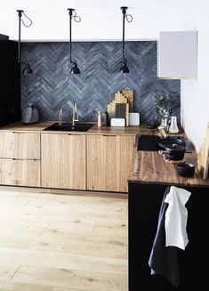 a kitchen with wooden cabinets and black appliances in it's center island, surrounded by hanging lights