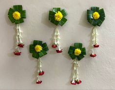 four pieces of paper with flowers and leaves attached to the sides, hanging on a wall